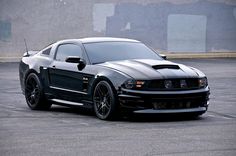 the black mustang is parked in an empty parking lot