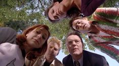 a group of people standing next to each other looking up at the sky with trees in the background