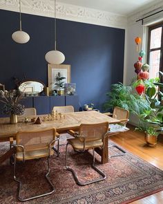 a dining room with blue walls and wooden table surrounded by chairs, potted plants