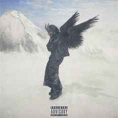 a black angel standing on top of a snow covered mountain