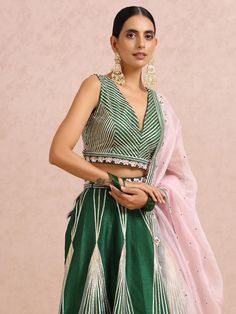 A three-piece Green Embroidered Stripe lehenga set with Sleeveless Blouse from the Label Nitika collection – Sunehra-Festive 2023. Featured here is a beautiful emerald green embroidered stripe and zig-zag pattern lehenga paired with a matching sleeveless blouse. The hand-embroidered folded floral sequins & beads in symmetry along with gold-silver gota stripes gives an elegant touch to this gorgeous paneled lehenga set. The V neck blouse has a cutout at the back with hook and tie-up tassel openin V Neck Lehenga, Royal Blue Lehenga, Flared Lehenga, Raw Silk Lehenga, Yellow Lehenga, Ivory Blouse, Green Lehenga, Blue Lehenga, Pink Lehenga