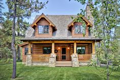 a large log home in the woods with porches and stonework on the front