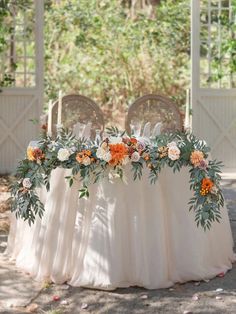 an outdoor table with flowers and greenery on it is set up for a wedding reception