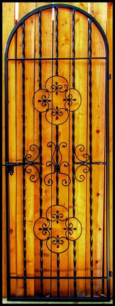 a wooden gate with wrought iron designs on it