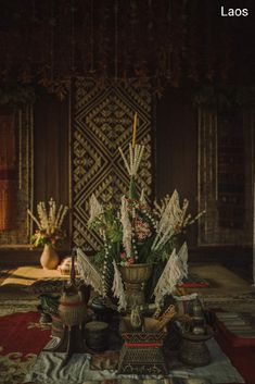 an arrangement of flowers in a vase on a table with other items and decorations around it