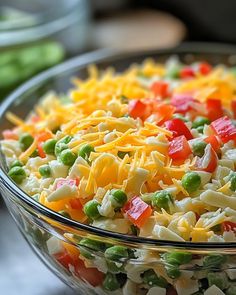 a salad with peas, carrots and cheese in a glass bowl