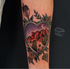 a heart shaped tattoo with cactus and mountains in the background