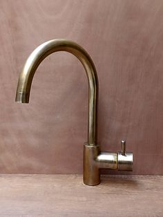 a brass colored faucet on a wooden table with a pink wall in the background