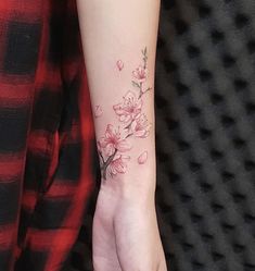 a woman's hand with a flower tattoo on her left wrist and the other arm