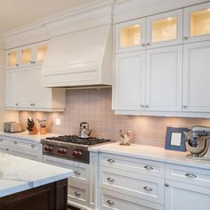 a kitchen with white cabinets and marble counter tops