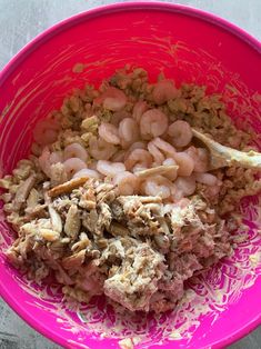 a pink bowl filled with food on top of a table