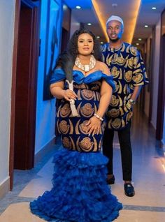 a man and woman dressed in african clothing standing next to each other on a hallway