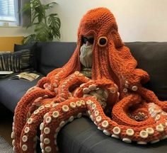 an orange knitted octopus sitting on top of a couch