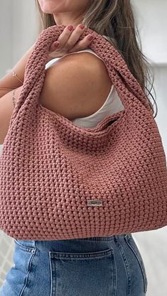 a woman is holding a pink knitted bag