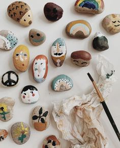 rocks with faces painted on them are next to a paintbrush and some other items