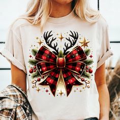 a woman wearing a t - shirt with a bow and reindeer antlers on it