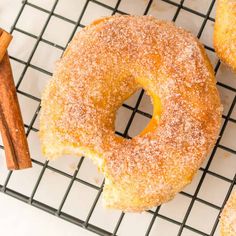 cinnamon sugar doughnuts on a cooling rack with cinnamon sticks and cinnamon stick next to them