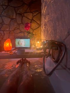 a person laying in a bath tub next to a laptop computer and candlelight candles