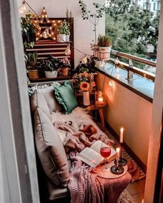 a small balcony with plants, candles and books on the table in front of it