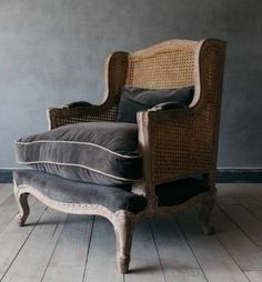 an old chair sitting on top of a hard wood floor next to a gray wall