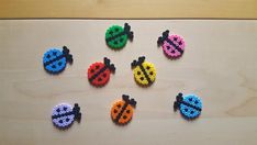 six ladybugs made out of beads on a wooden surface