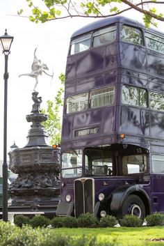 a purple double decker bus parked in front of a lamp post on the side of a road