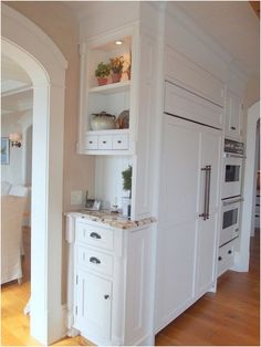 a kitchen with white cabinets and an island in the middle of the room that is built into the wall