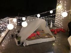 an outdoor bed with lights and decorations on the roof at night, in front of a building