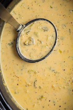 a ladle in a pot filled with broccoli and cheese soup, ready to be cooked