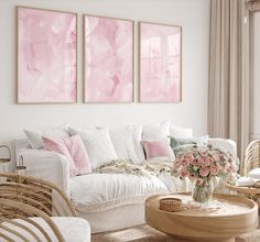 a living room filled with white furniture and paintings on the wall above it's windows