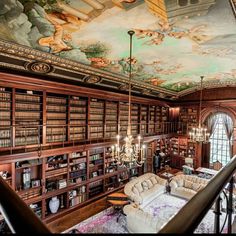 the library is full of books and chandeliers, with paintings on the ceiling