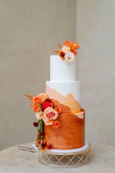 a white and orange wedding cake with flowers on top