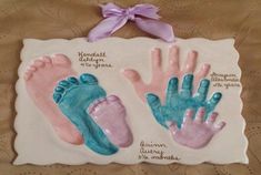 two ceramic handprints with baby's feet and hands on them, one is pink and the other is blue