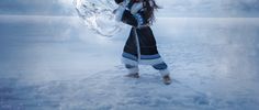 a woman standing in the snow holding an umbrella