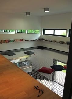 an indoor swimming pool in a house with wood flooring and white walls, surrounded by windows