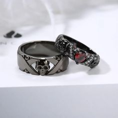 two wedding rings with skulls on them sitting on a white table top next to each other