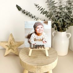 a wooden stool with a small photo on it next to a potted plant and star