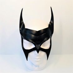 a white mannequin head wearing a black mask with horns on it's face