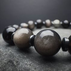 "Discover the harmonious blend of style and spiritual strength with our 8mm Silver Obsidian Stone Beaded Bracelet. Crafted for both men and women, this bracelet features genuine Silver Obsidian beads on a stretch cord, offering comfort and flexibility. The 925 Sterling Silver accents add an elegant touch to this protective accessory. Experience the grounding influence on the Root chakra, thanks to the powerful properties of Silver Obsidian. Ideal for those seeking a stylish protection bracelet, Polished Round Obsidian Bead Jewelry, Obsidian Round Beads Jewelry 8mm, Silver Obsidian, Spiritual Strength, Energy Balancing, Obsidian Stone, Hematite Bracelet, Protection Bracelet, Handmade Jewelry Gift