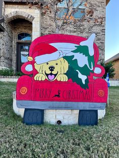 a dog is sitting in the back of a red truck with a christmas tree on it