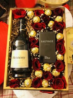 a wine bottle and two chocolates in a box with roses on the table next to it