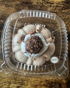 a plastic container filled with donuts covered in icing and nuts on top of a wooden table