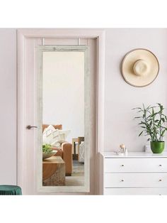 a white door with a mirror on the side and a plant in front of it