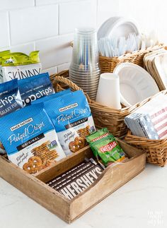 a basket filled with snacks sitting on top of a counter next to plates and cups