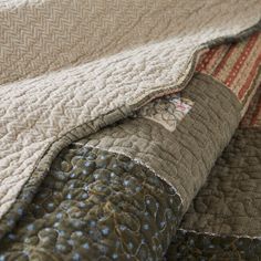 a close up of a quilted bed spread on top of a bed with two pillows