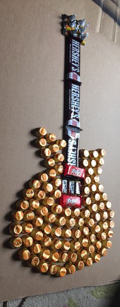 a guitar made out of beer bottle caps and candy bar wrappers on top of it