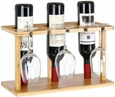 three wine bottles and two glasses on a wooden shelf with glass holders in the middle