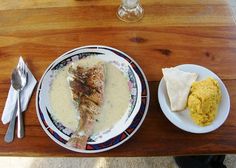 two plates with food on them sitting on a wooden table next to silverware and utensils