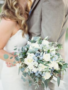 the bride and groom are kissing in front of each other with flowers on their bouquets