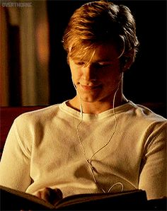 a young man is listening to music on his headphones while sitting down and reading a book